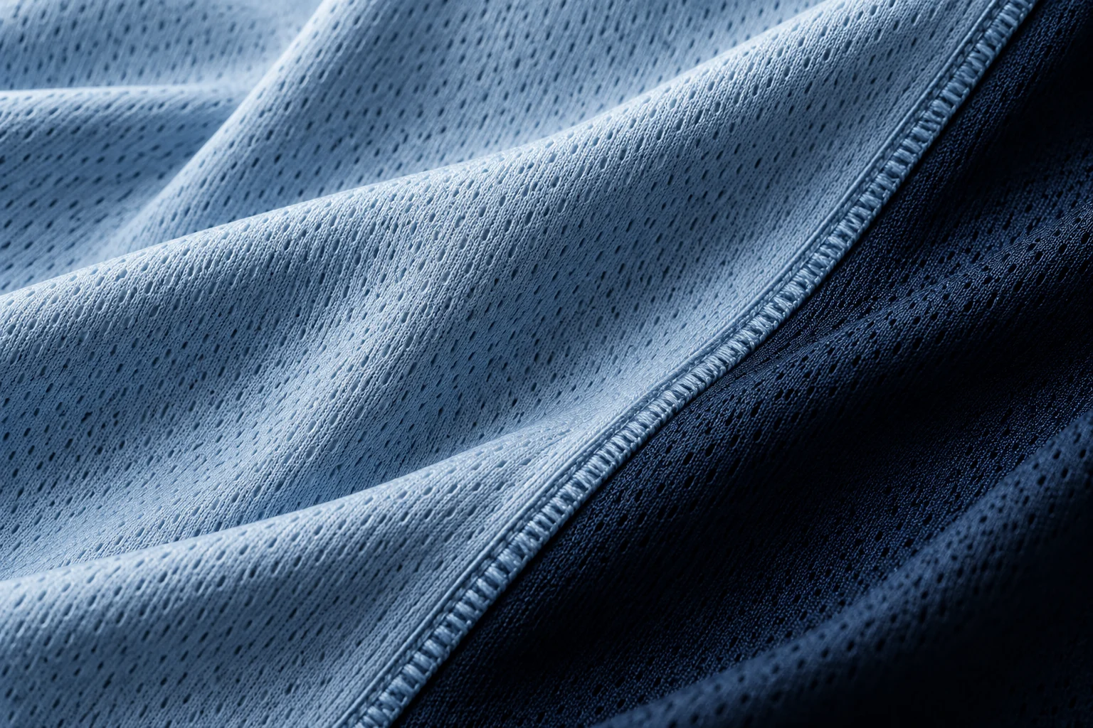 Illustrative close-up of ice-blue technical knit and a navy seam