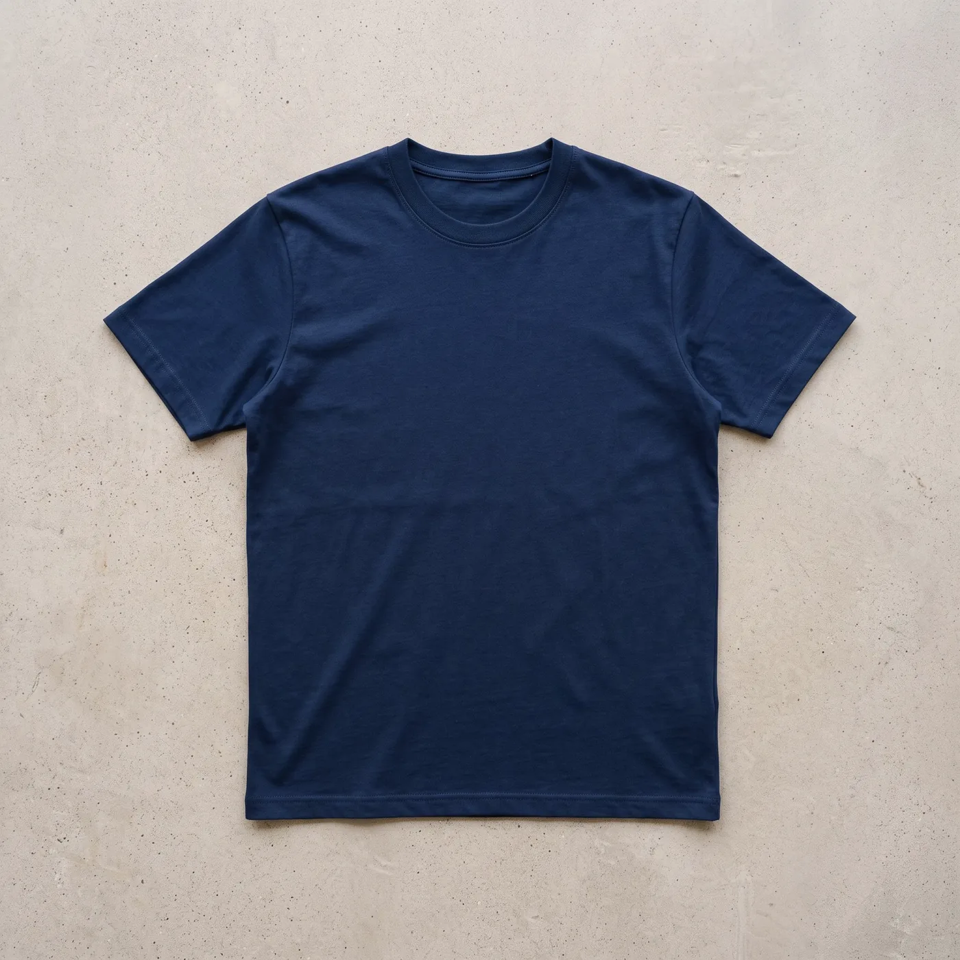 Plain navy t-shirt laid flat on concrete