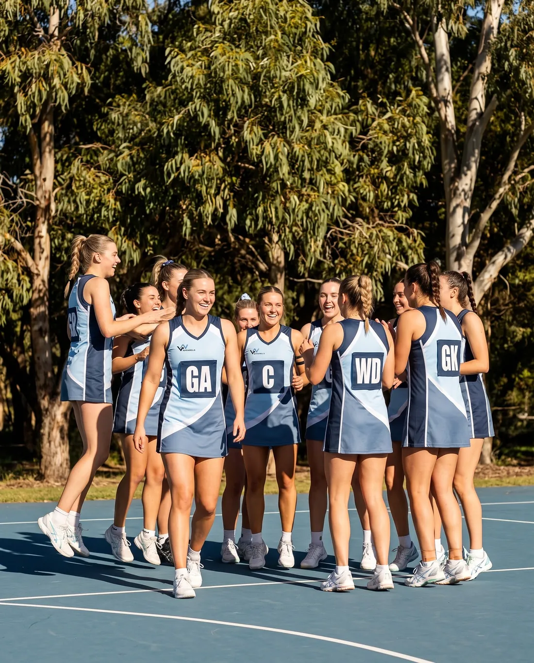 Netball team in sky-blue and navy dresses celebrating on an outdoor court